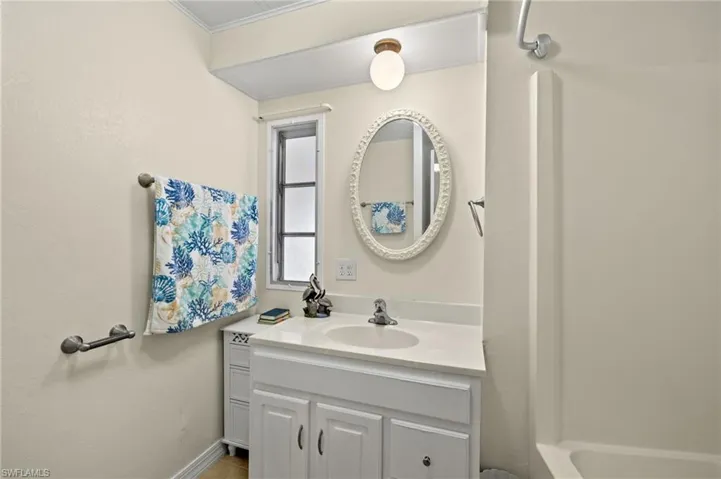 Bathroom featuring a bath, ornamental molding, and vanity