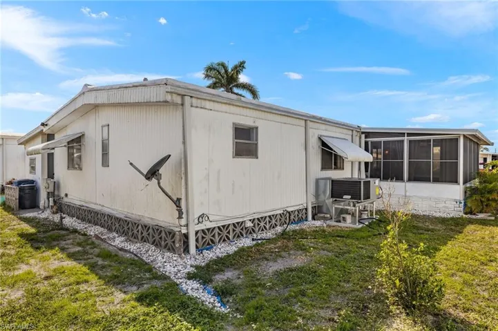 View of side of property featuring a sunroom, central AC unit, and a lawn