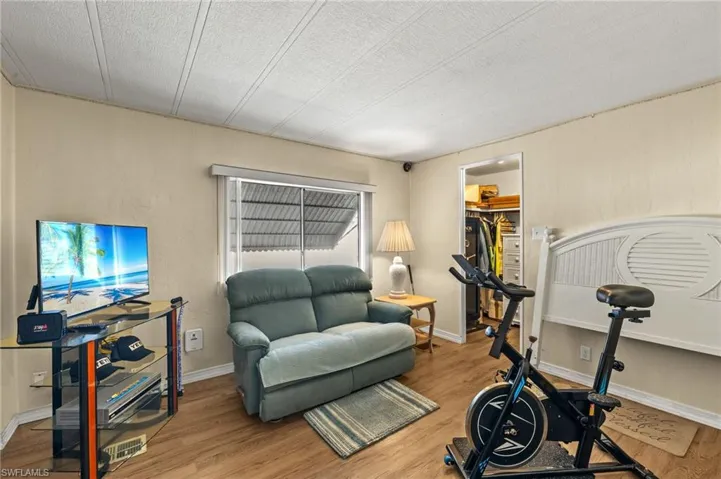 Workout room featuring a textured ceiling, baseboards, and wood finished floors