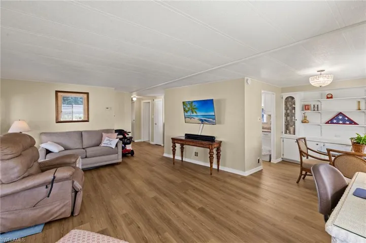 Living area with built in features, an inviting chandelier, baseboards, and luxury vinyl