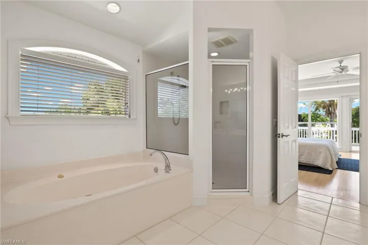 Bathroom featuring plus walk in shower, ceiling fan, and tile patterned floors