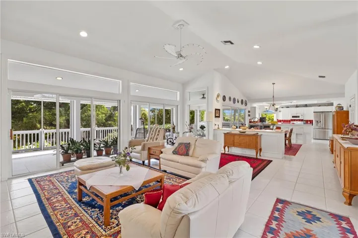 Tiled living room with ceiling fan and high vaulted ceiling