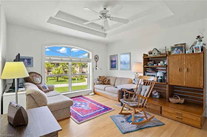 Living room with a tray ceiling, light hardwood / wood-style flooring, and ceiling fan