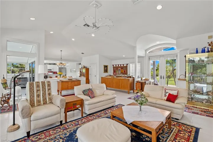 Living room with a healthy amount of sunlight, light tile patterned floors, and lofted ceiling