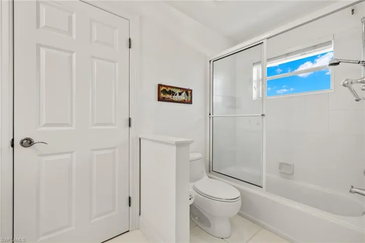 Bathroom featuring tile patterned floors, toilet, and enclosed tub / shower combo