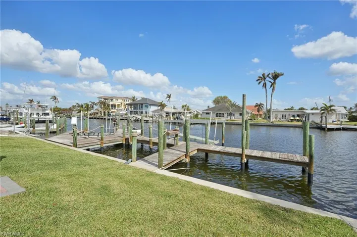 Dock area with a water view and a lawn