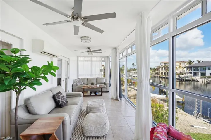 Sunroom / solarium featuring a wall mounted air conditioner, a water view, and ceiling fan