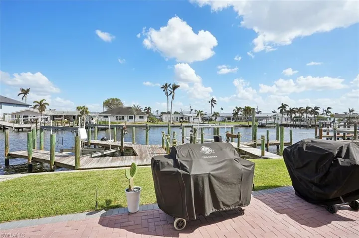 View of dock with a water view and a lawn