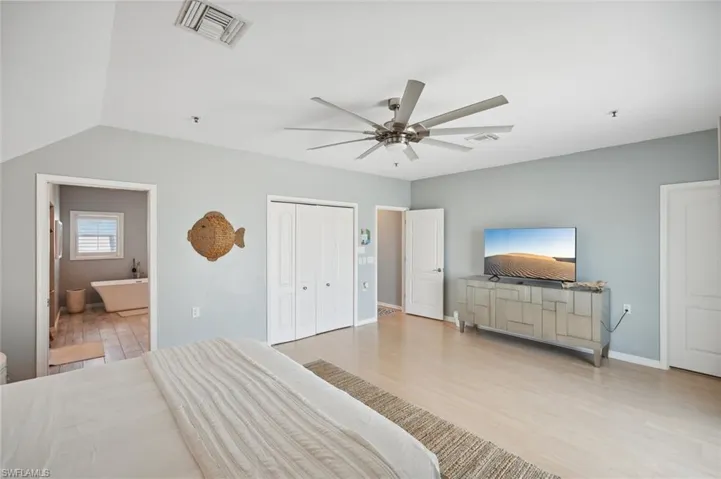 Bedroom featuring lofted ceiling, a closet, light hardwood / wood-style flooring, ensuite bathroom, and ceiling fan