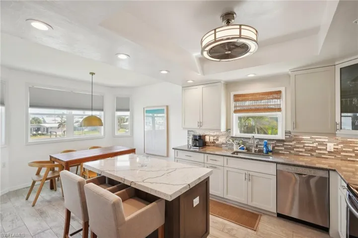 Kitchen featuring tasteful backsplash, appliances with stainless steel finishes, sink, light hardwood / wood-style floors, and decorative light fixtures