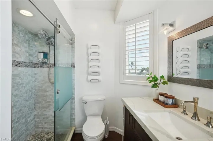 Bathroom with vanity, a shower with shower door, and toilet