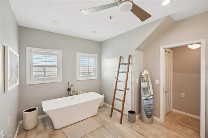 Bathroom featuring hardwood / wood-style flooring, a bath, and ceiling fan