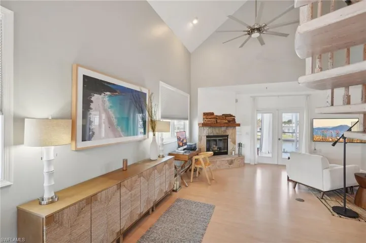 Living room with light hardwood / wood-style floors, a fireplace, high vaulted ceiling, and plenty of natural light