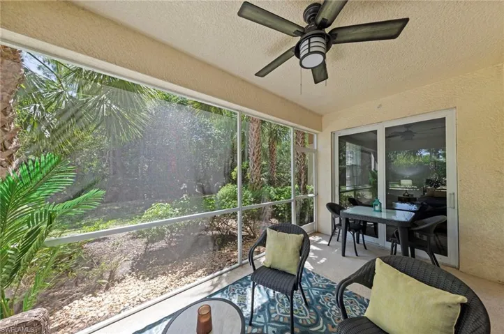 The property features a screened-in patio with a ceiling fan, offering views of surrounding palm trees and greenery
