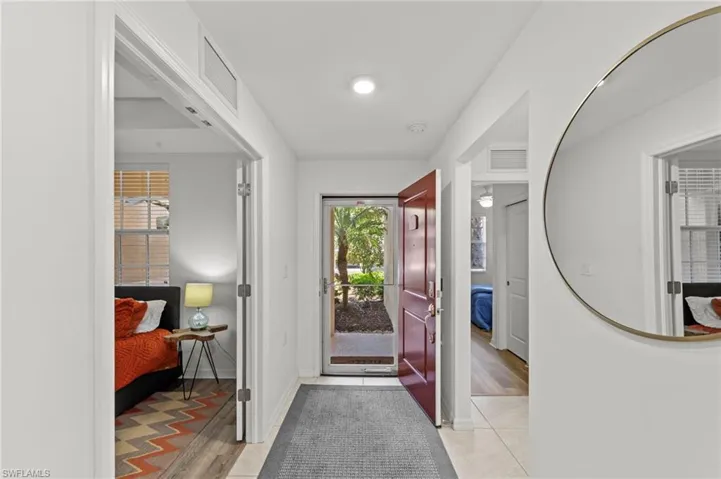 Entryway featuring a red front door, tiled flooring, and a round wall mirror
