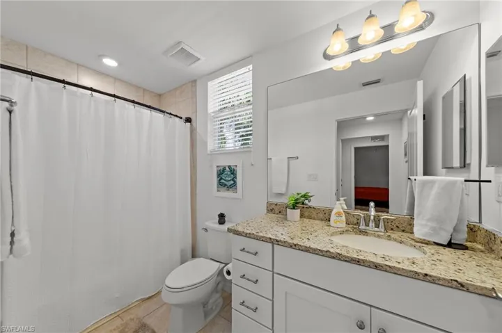 Bathroom with a white vanity featuring a granite countertop, an integrated sink, and chrome fixtures
