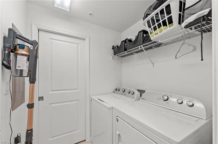 Utility room featuring a washer and dryer, a wire shelving unit, and white walls