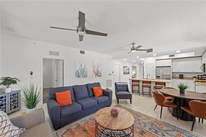 Open-concept living area featuring a kitchen with white cabinetry and stainless steel appliances, a dining area, and living room