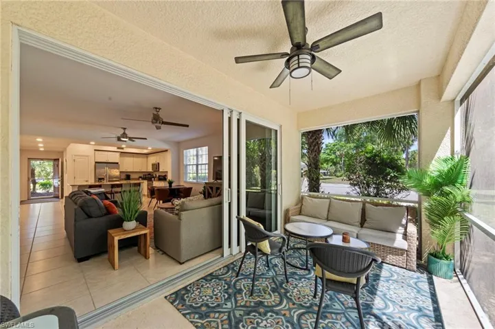 Expansive screened patio featuring a ceiling fan, tiled flooring, and views of the surrounding area, with sliding glass doors opening to the living area and kitchen