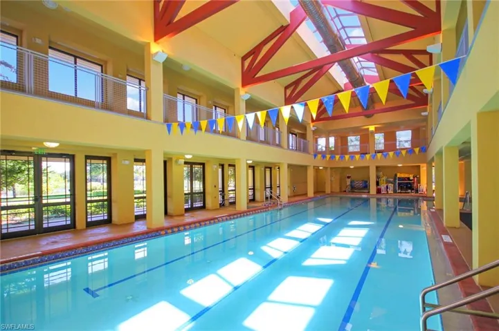 Indoor swimming pool featuring a skylight, high ceilings with exposed beams, and glass doors providing views of the outdoors