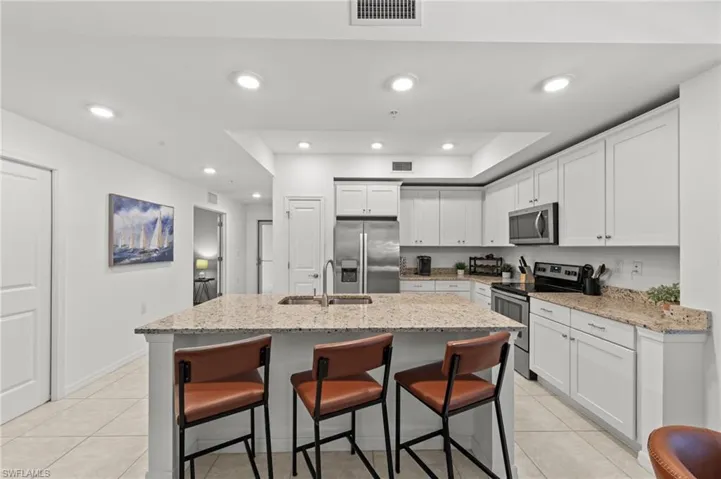 The kitchen features white cabinetry, stainless steel appliances, and granite countertops