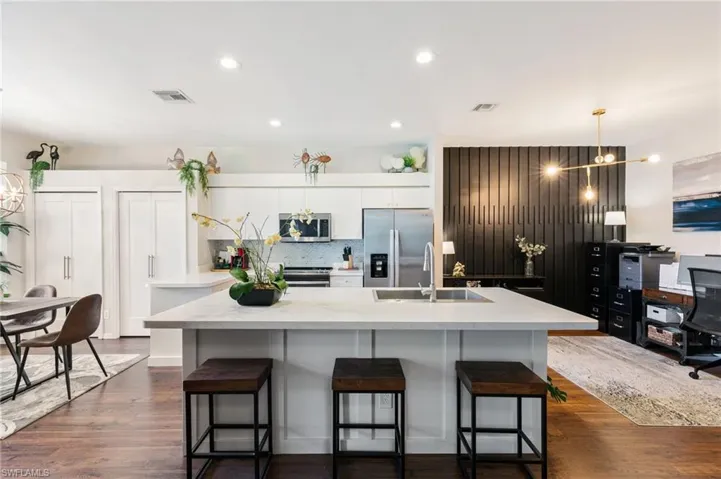 Kitchen with visible vents, appliances with stainless steel finishes, a kitchen island with sink, light countertops, and a sink