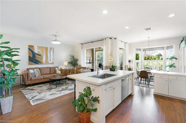 Kitchen featuring pendant lighting, dark wood-type flooring, dishwasher, a sink, and light countertops