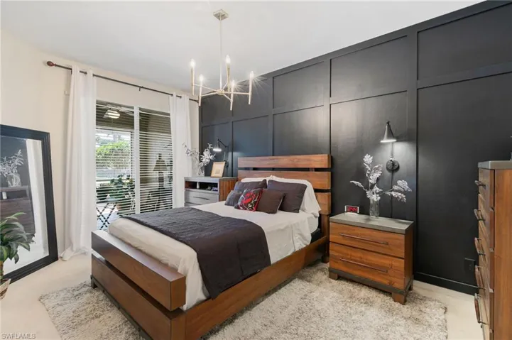 Bedroom featuring access to outside, a decorative wall, a notable chandelier, and light colored carpet