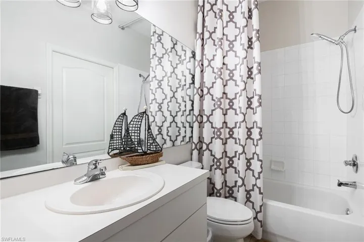 Bathroom with toilet, shower / bathtub combination with curtain, and vanity