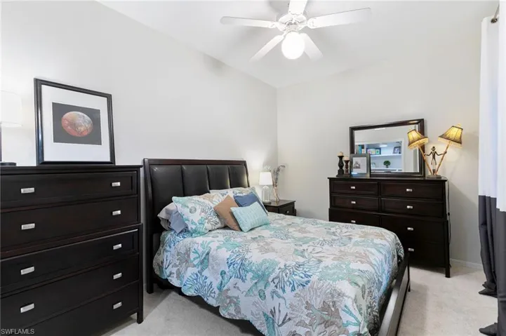 Bedroom featuring light carpet, baseboards, vaulted ceiling, and ceiling fan