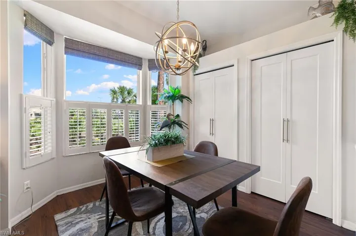Dining space featuring dark wood-style flooring, baseboards, and an inviting chandelier