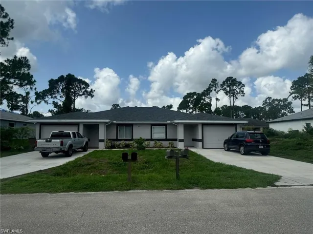 Ranch-style house with a garage, driveway, a front yard, stucco siding, and roof with shingles