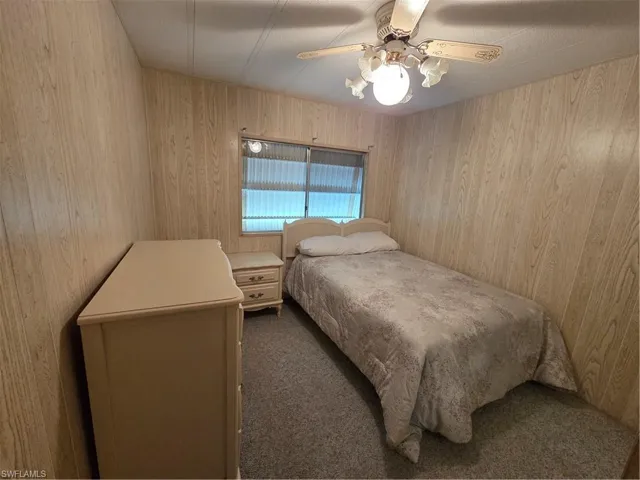 Guest bedroom with neutral carpet and ceiling fan.