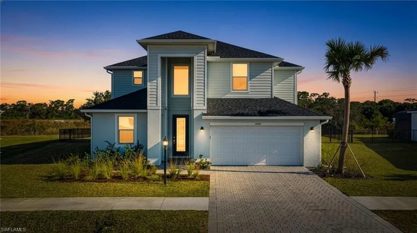 View of front facade featuring decorative driveway, a shingled roof, a garage, and stucco siding