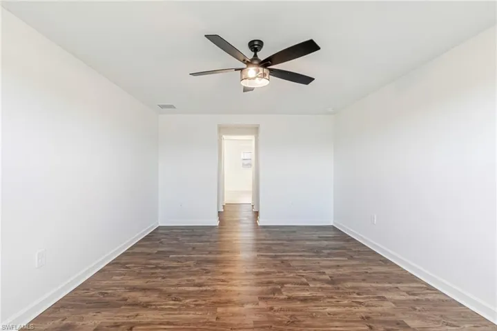 Spare room with dark wood-style floors and a ceiling fan