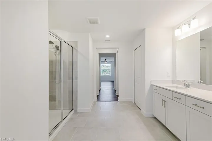 Bathroom featuring vanity, a stall shower, a closet, light tile patterned floors, and recessed lighting