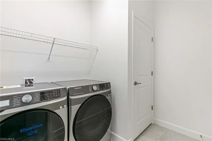 Laundry area with independent washer and dryer and light tile patterned floors