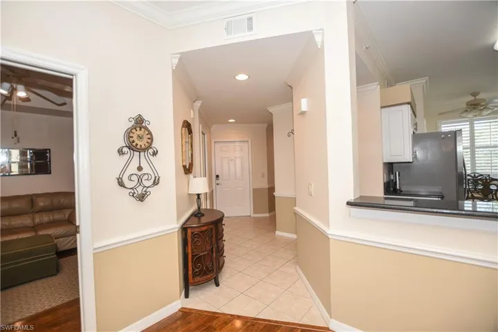 Corridor with crown molding, recessed lighting, light tile patterned floors, baseboards, and visible vents