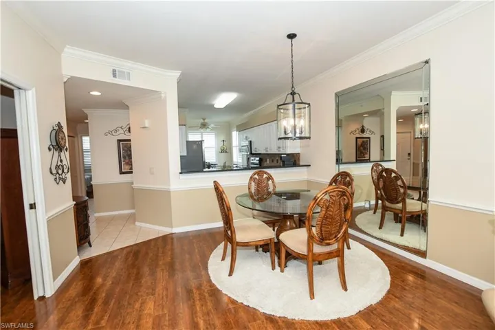 Dining space featuring crown molding, wood finished floors, ceiling fan with notable chandelier, baseboards, and visible vents