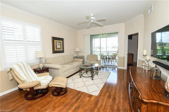 Living room with dark wood-style floors, ceiling fan, ornamental molding, and baseboards