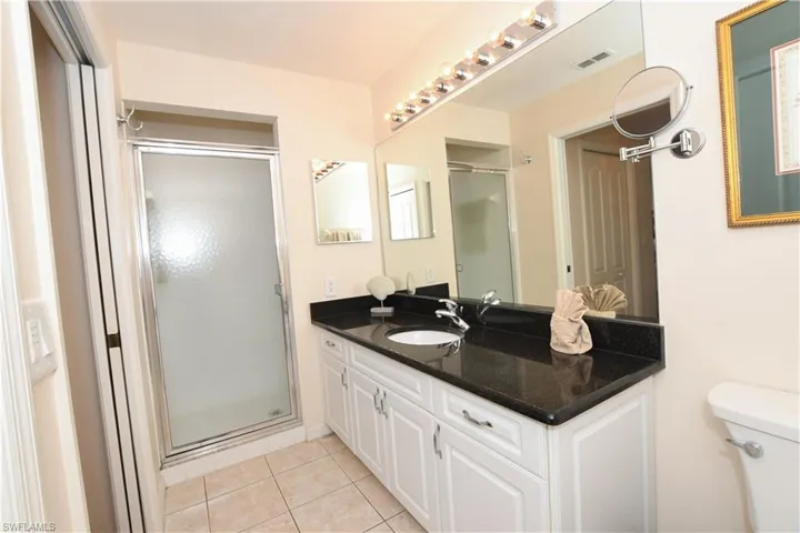 Bathroom with visible vents, toilet, vanity, a stall shower, and tile patterned flooring