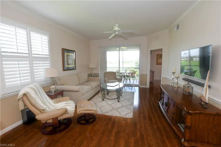 Living area with crown molding, baseboards, visible vents, ceiling fan, and wood finished floors