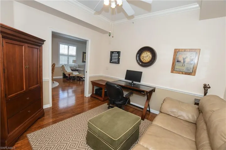 Home office with baseboards, dark wood-style flooring, ceiling fan, and ornamental molding
