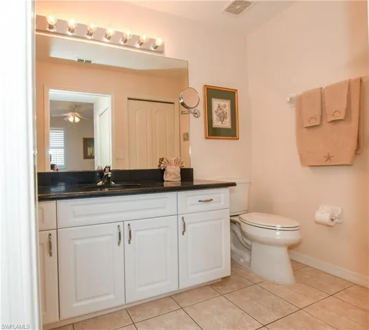 Bathroom with tile patterned floors, vanity, toilet, and visible vents