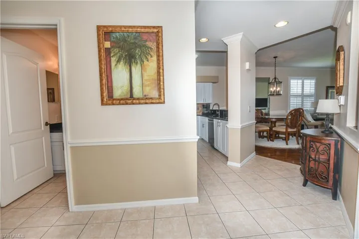Hallway with light tile patterned flooring, a chandelier, ornamental molding, recessed lighting, and a sink