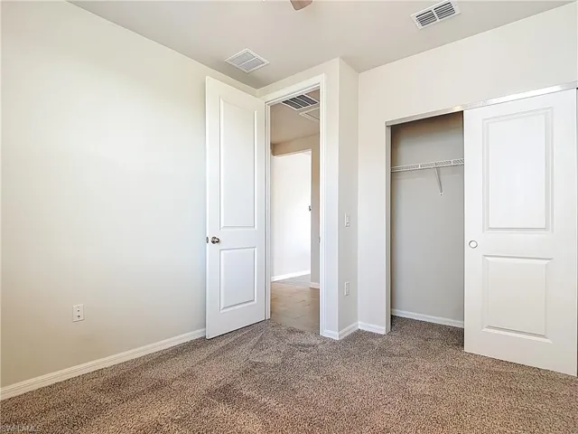 Unfurnished bedroom featuring carpet, a closet, and a ceiling fan