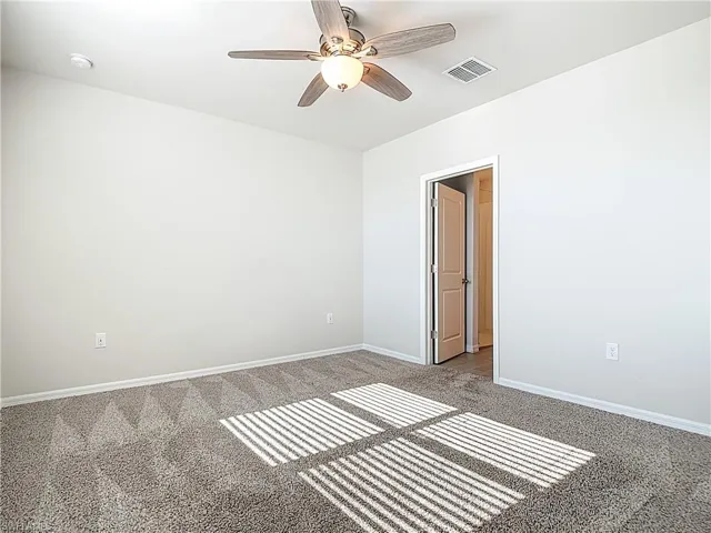 Carpeted empty room with baseboards and a ceiling fan
