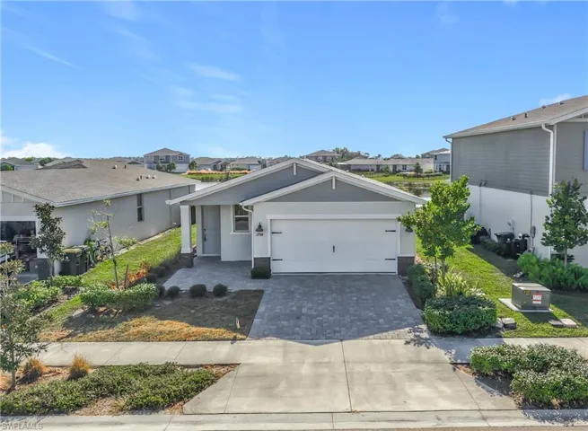 View of front of house featuring decorative driveway, a garage, stucco siding, and a residential view
