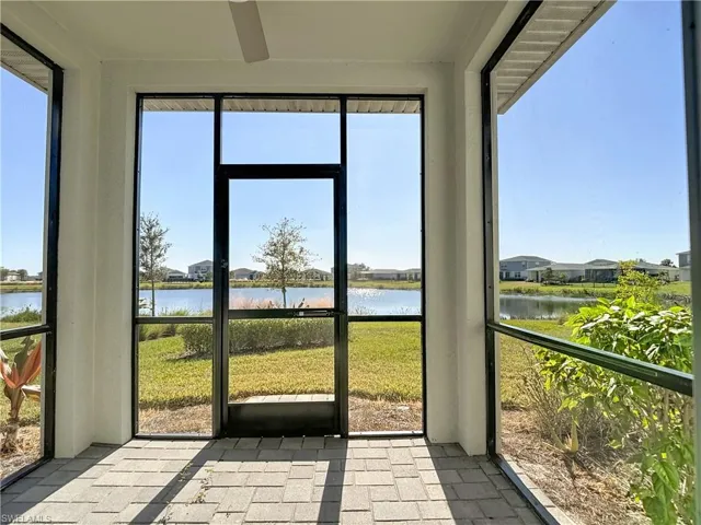 Unfurnished sunroom featuring a water view, a residential view, and ceiling fan