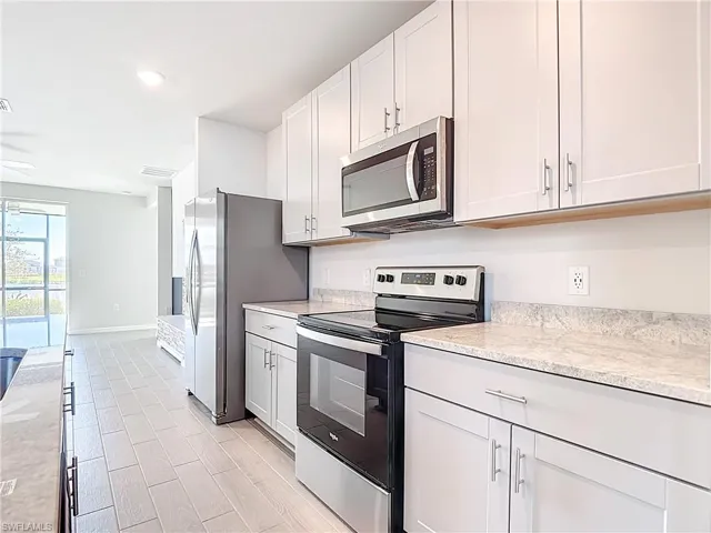 Kitchen with appliances with stainless steel finishes, white cabinets, light wood finished floors, and recessed lighting